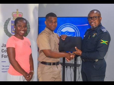 Territorial Officer in the St Catherine North Police Division, Inspector Ishmael Williams, presents student of the Spanish Town-based Eltham High School, Justine Stone , with a laptop, donated by Donique Sinclair-Chambers (left), during a recent handover c