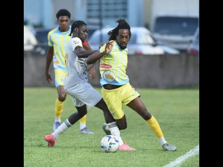 Jerome McLeary (centre) of Cavalier  challenges Waterhouse’s Omani Leacock during their Jamaica Premier League match at the Drewsland Mini Stadium yesterday. Home team Waterhouse won the game 2-1. 