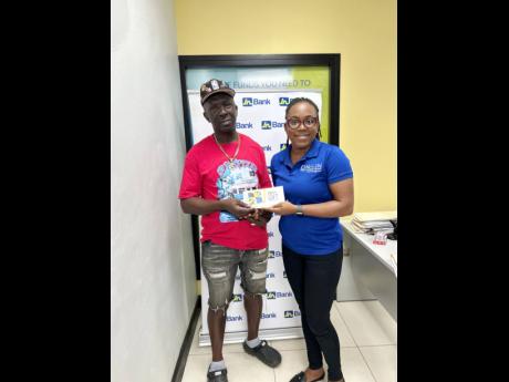 Roy Lamey accepts a grant from Marsha Salmon-Ebanks, client relations manager, JN Bank Small Business Loans Division, as part of the bank’s recovery efforts for small business operators affected by Hurricane Melissa.
