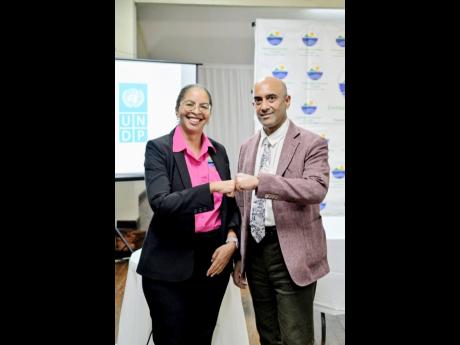 Nicole Adamson, CEO of the Environmental Foundation of Jamaica (EFJ) (left), and Dr. Kishan Khoday, Resident Representative of the UNDP Multi Country Office in Jamaica, share a fist bump after signing a Memorandum of Understanding to scale up climate‑act