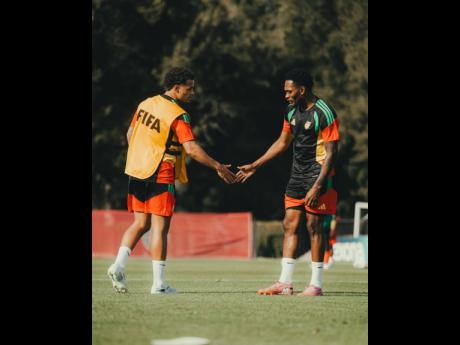 Credit: Courtesy of JFF Media Reggae Boyz Bailey Cademarteri (left) and Renaldo Cephas greet each other during a training session in Mexico.