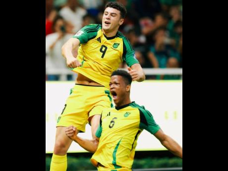 Reggae Boyz players Bailey Cadamarteri (left) and Richard King ceelebrate the former's 18th-minute goal during a FIFA playoff game against New Caledonia at the Guadalajara Stadium yesterday.