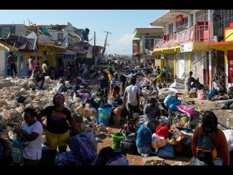 Residents gather amid debris in the aftermath of Hurricane Melissa on a street in Black River, Jamaica, on October 30, 2025. 