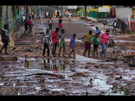 People walk through Santa Cruz, Jamaica, after Hurricane Melissa passed.