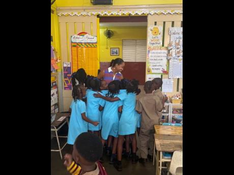 Credit: Contributed Talia Parkinson-Jones surrounded by students at Wolmer’s Preparatory School during a visit to her alma mater.