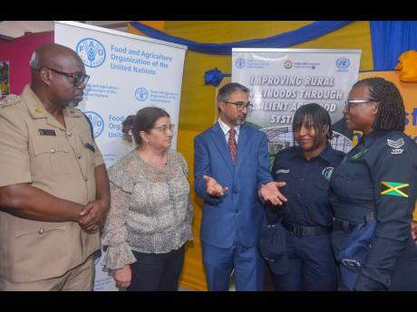 Indian High Commissioner to Jamaica, His Excellency Mayank Joshi (centre), makes a point to Head of the Guanaboa Vale Police, Sergeant Navelette Davis-Leachman (right), and Constable Leonie Angus (second right), during the recent certification ceremony for