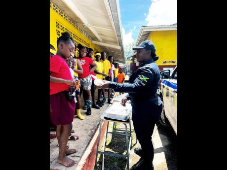 Corporal Chevon McKoy serves bun and cheese to students at Jubilee Primary School on Wednesday. 