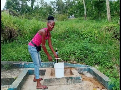 Credit: Photo by Carl Gilchrist A resident of Beecher Town, St Ann, collects water from a community standpipe.