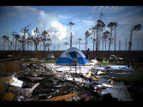 Credit: AP This 2019 photo shows a man searching in the rubble of his house destroyed by Hurricane Dorian in Rocky Creek East, Grand Bahama, Bahamas.
