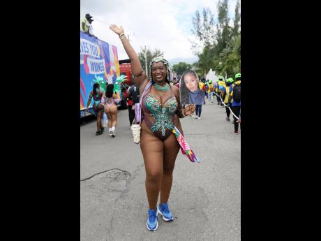 Kia-Simone Bell of Yard Mas parades along East Kings House Road on Sunday, carrying a photo poster of her absent friend while celebrating Carnival in Jamaica’s road march.