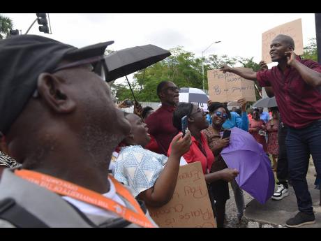 Dennis Samuels (right), Union Representative at the University of the West Indies (UWI), addresses employees at both the University of the West Indies (UWI) and University Hospital of the West Indies (UHWI) who demonstrated outside the gates of the UWI for