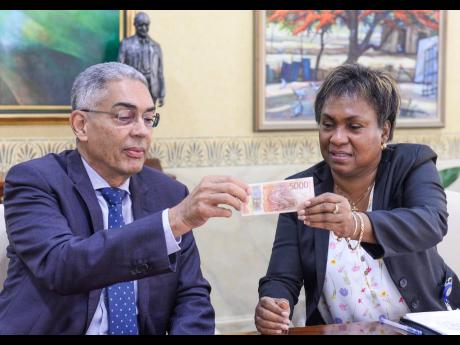 
Bank of Jamaica (BOJ) Governor Richard Byles (left) examines features on the new $5,000 note, being highlighted by BOJ Division Chief for Banking and Currency Operations, Chevanese Morais.