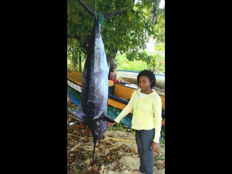 Female fisher Sashae Shaw stands next to a fish at the Old Marina, in Portland, recently. 