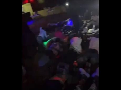 Credit: Contributed Patrons lay flat in Mt James, St Andrew venue as directed by police. The police swooped down on the venue in search of wanted men and illegal firearms.