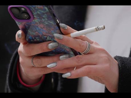 A woman smokes on a street in London on April 16, 2024. (AP Photo/Kin Cheung, File)