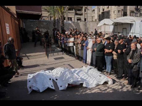 Palestinians pray beside the bodies of men killed in an Israeli strike, during their funeral at Nasser Hospital in Khan Younis, southern Gaza Strip, Tuesday, April 21, 2026.